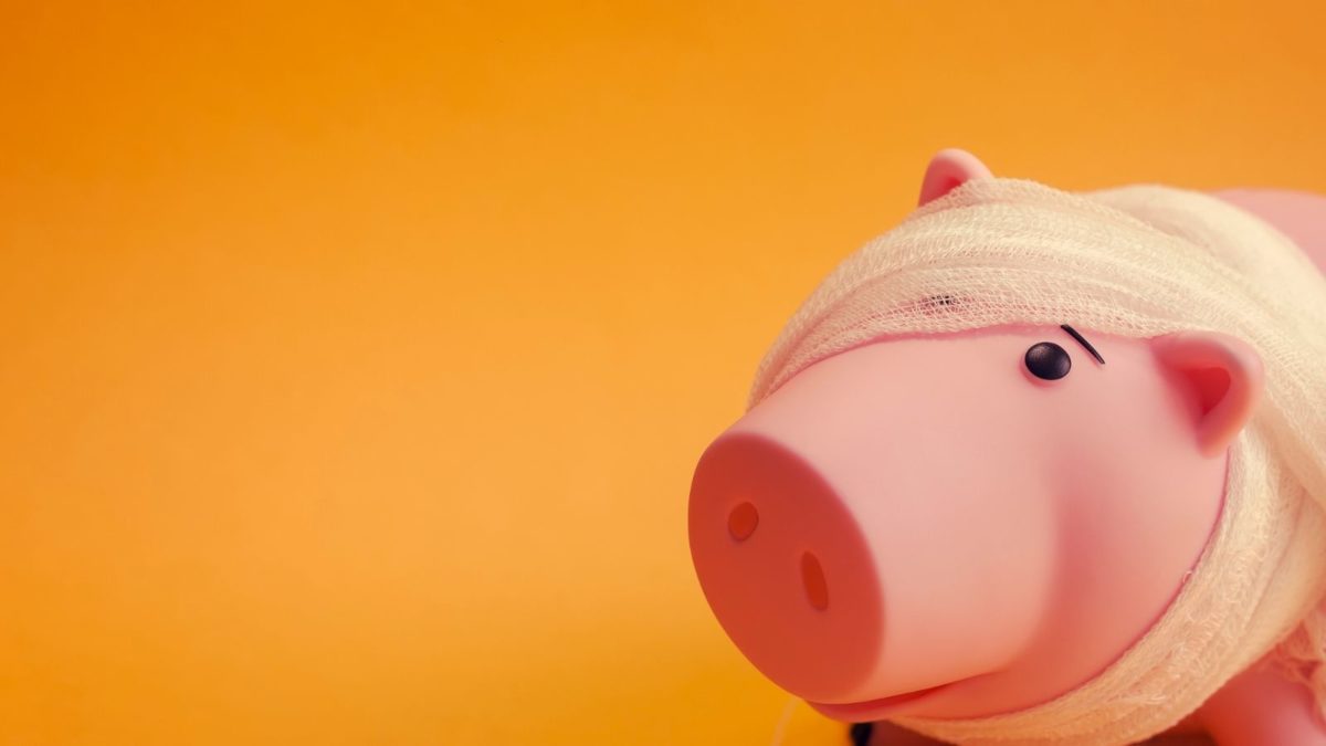 Pink piggy bank with bandage against orange